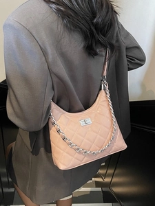 Pale pink quilted crossbody bag with silver chain strap worn over a dark grey blazer