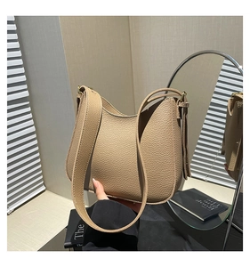 Détail d'un sac à bandoulière en cuir grainé marron avec une forme demi-lune minimaliste