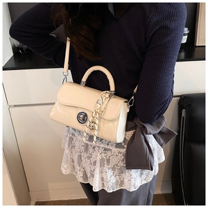 Détail du sac bandoulière crème avec fermoir rotatif argenté et foulard à carreaux