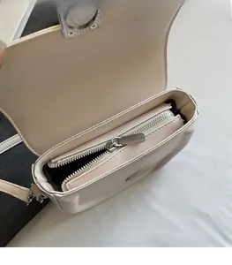 Detailed view of cream saddle bag featuring smooth silver zipper and interior lining