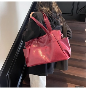 Close-up of a burgundy leather tote bag showing multi-pocket detail on model's shoulder