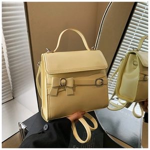 Detail van crèmegele PU-lederen tas met een elegante strik en metalen gesp-versiering