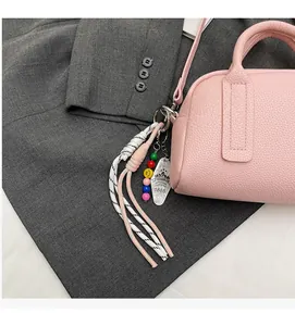 Pink lychee texture leather handbag featuring colorful bead charms and woven rope detail
