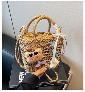 Detail of woven straw bucket bag with cute plush bear and colorful bow charms