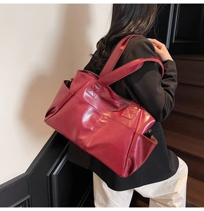 Burgundy faux leather tote bag with reinforced handles shown in a lifestyle street setting