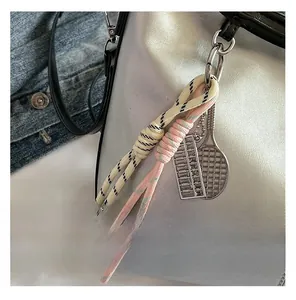Detail of woven rope charms with tennis racket and abacus pendants on a bucket bag