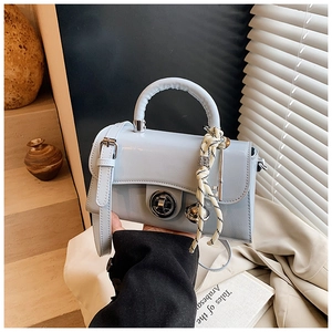 Détail du sac bandoulière en cuir verni bleu clair avec fermoir anneau et breloques