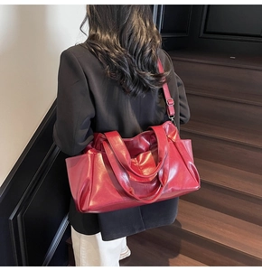 Model wearing dark red leather handbag showing large capacity and adjustable strap