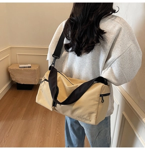 Sac polochon kaki en toile avec bandoulière noire et broderie porté par un mannequin
