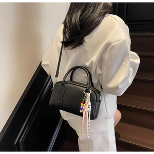 Detail of black pebbled leather mini Boston bag with top handle and beaded charm