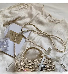Detail of straw bucket bag with white ribbon bow and star charm alongside a beige top
