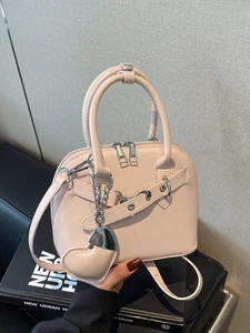 Pink shell bowling bag with double zipper and heart charm in a hand-held lifestyle view