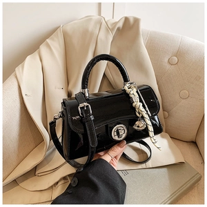 Détail du sac à main en cuir verni noir avec fermoir argenté et poignée élégante