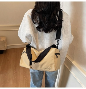 Détail d'un sac Boston en toile beige avec bandoulière noire et poche latérale zippée