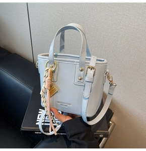Close-up of light blue bucket bag with gold hardware and pink abacus charm detail