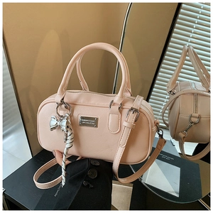 Detail of light pink Boston bag with silver bow charm and textured leather finish