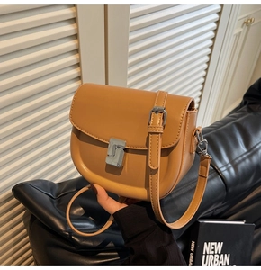 Detail of adjustable leather strap and silver metal buckle on tan saddle bag