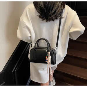 Detail of black lychee grain leather boston bag with colorful beaded tassel pendant
