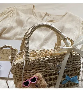 Close-up of straw bucket bag with bear charm, star pendant, and blue silk bow detail