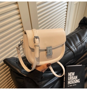 Detail view of cream saddle bag with silver metal push buckle and adjustable strap