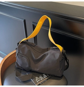 Détail du sac Boston en nylon noir avec bandoulière jaune et poches zippées