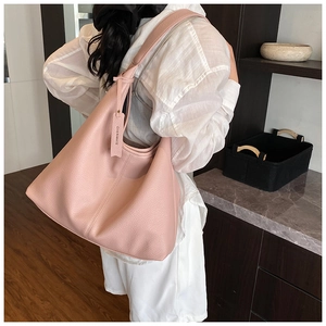 Close-up of pink litchi grain leather hobo bag showing texture and decorative tag detail