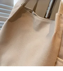 Dettaglio ravvicinato della borsa tote in tela beige con scritta MIDOLAI e trama
