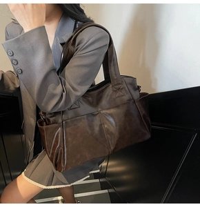 Detail of vintage dark brown tote bag featuring large double front pockets and side storage
