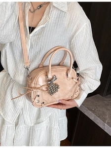 Sac Boston rose avec décoration nœud et breloque cœur porté par un mannequin élégant