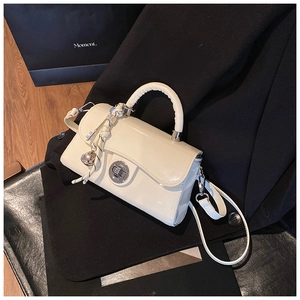 Détail du mini sac bandoulière en cuir verni crème avec fermoir rotatif argenté et nœud