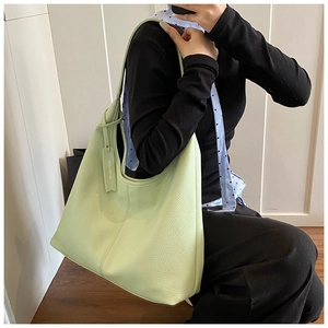 Close-up of light green lychee texture leather tote bag with elegant hanging brand tag