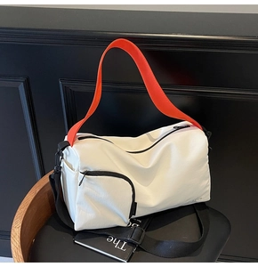 Détail du sac Boston en toile avec poignées orange vif et bandoulière tissée noire