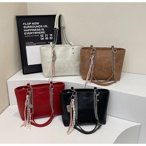 Detail view of large PU leather tote bags in white, brown, red, and black with tassels