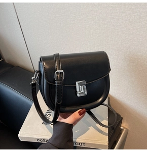 Detailed macro view of the sleek silver geometric metal buckle on a black saddle bag