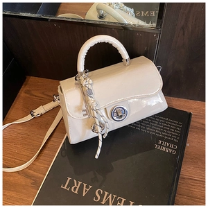 Détail du sac bandoulière blanc crème en cuir avec fermoir métallique et breloque tressée