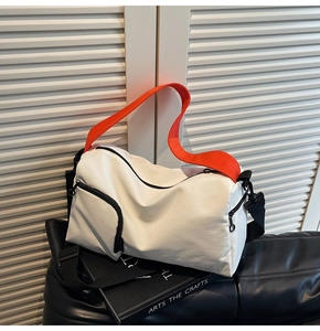 Détail du sac Boston en nylon blanc avec poignée orange et bandoulière noire