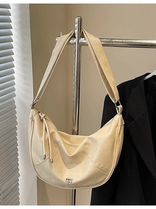 Sac à bandoulière demi-lune blanc crème avec logo métallique et détail de pompon zippé