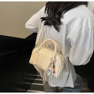 Detail of cream white leather Boston bag with colorful beads and 1885 pendant