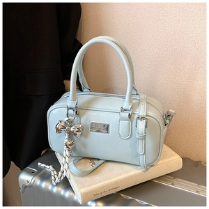 Detail of light blue Boston bag with silver heart charm and leather buckle accents