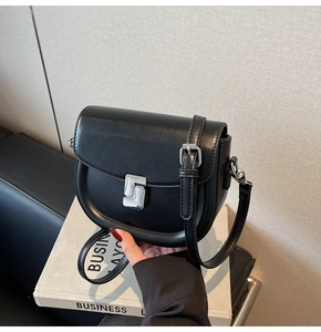 Detail shot of black leather saddle bag with silver buckle on minimalist book box