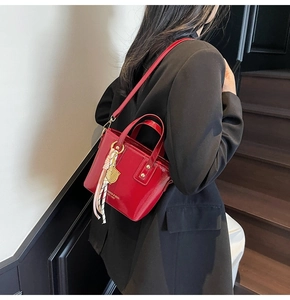 Detail of red patent leather bucket bag with glossy finish and silk scarf accessory