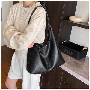 Close-up of black lychee grain leather tote bag featuring a metallic logo hangtag detail