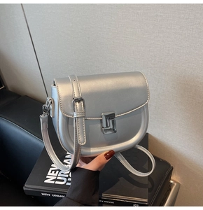 Silver metallic saddle bag featuring a unique L-shaped geometric metal clasp and strap