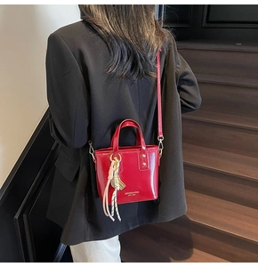 Detailed macro shot of a glossy red crossbody bucket bag with elegant silk scarf handle
