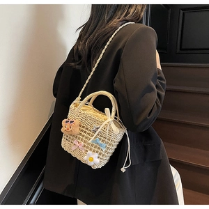 Detail of woven straw bucket bag featuring cute bear charms and a drawstring closure