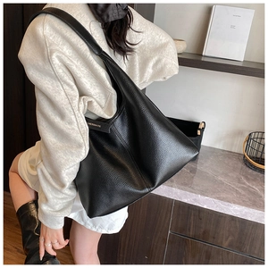 Detail of black pebbled leather tote bag showing large capacity and side brand strap
