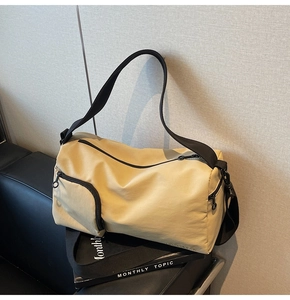 Détail du sac Boston en nylon jaune avec poche zippée et logo de marque sur canapé cuir