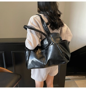 Detailed view of black faux leather tote bag with side pockets on female model shoulder