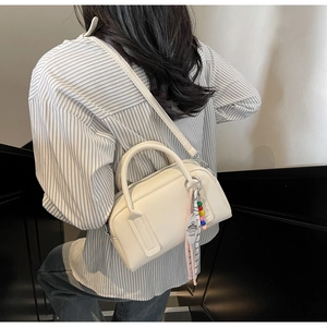 Detail of cream white litchi grain leather mini pillow bag with beaded pendant