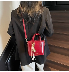 Back view of model wearing a bright red patent leather mini tote bag with gold lettering